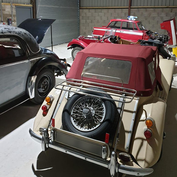 a classic car with a red sunroof in a workshop