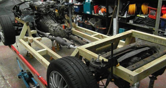 the bare chassis of a classic car being installed with new components