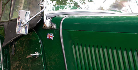 the side view of a 1946 green vintage MGTC convertible car with the Union Jack on the side