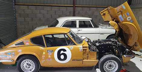 a classic yellow race car with its engine exposed